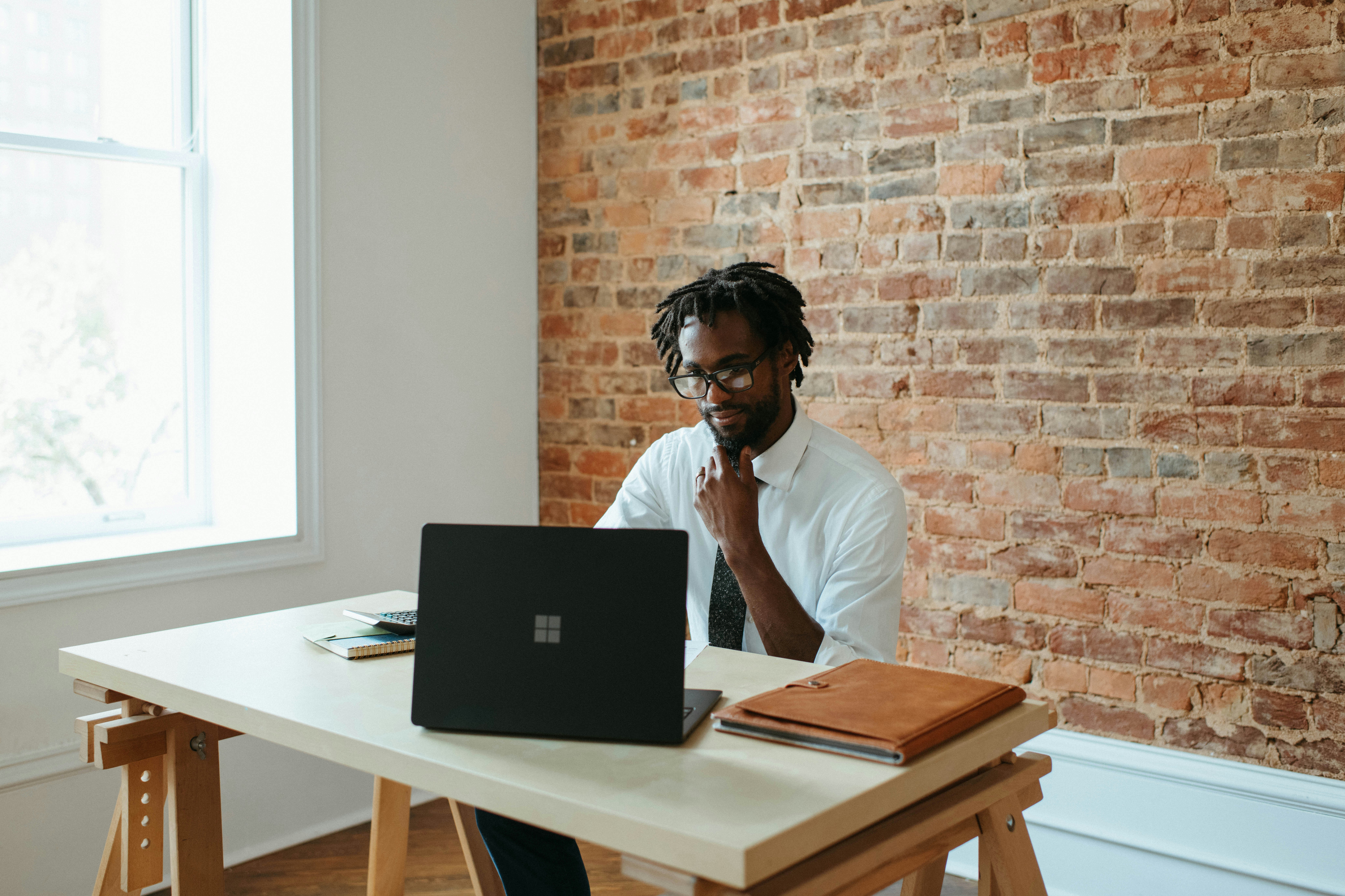 Man looking at his Microsoft laptop with his hand on his chin
